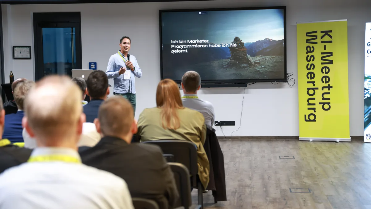 Pedro Wiechers spricht beim KI-Meetup Wasserburg vor Publikum, auf dem Bildschirm die Folie: Ich bin Marketer. Programmieren habe ich nie gelernt.